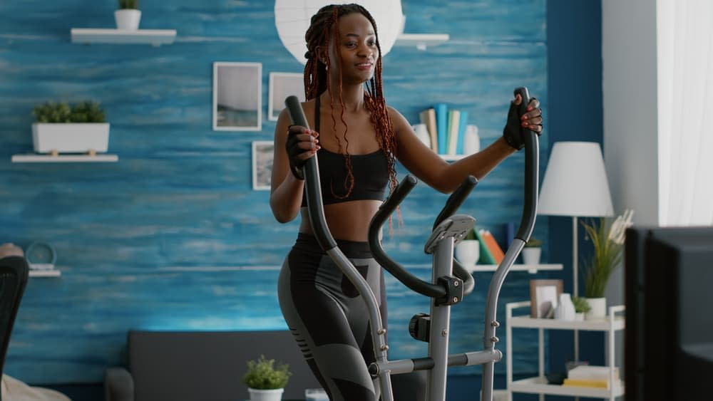 A young woman doing elliptical cross trainer exercise in her home