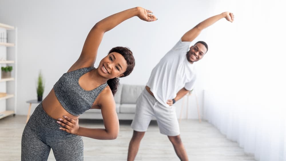 Couple Doing the Side Stretch Before Their Exercise Bike Workout