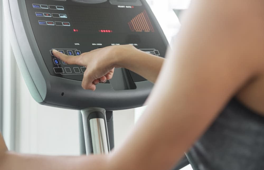 Person pressing the button on the console of the elliptical machine to adjust the incline level