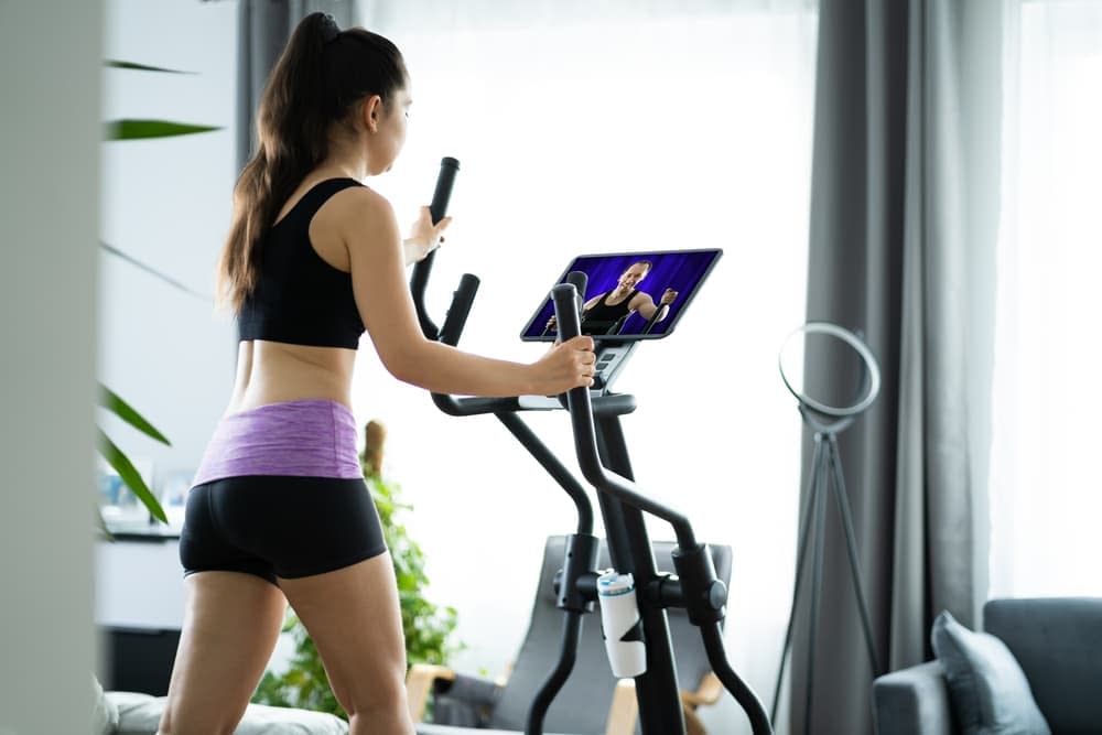 Girl working out on an elliptical trainer that has a smart display