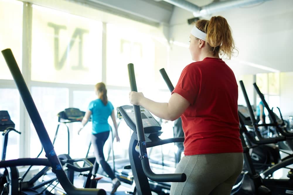 Woman working out on the elliptical machine in a gym - does the elliptical work your stomach