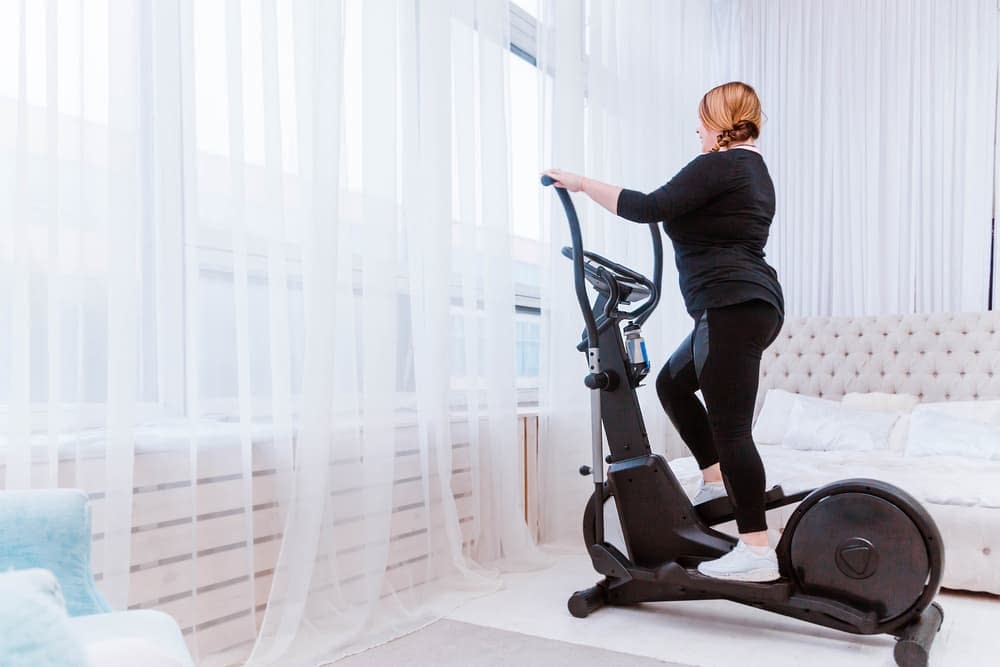Woman exercising on an elliptical machine in her bedroom