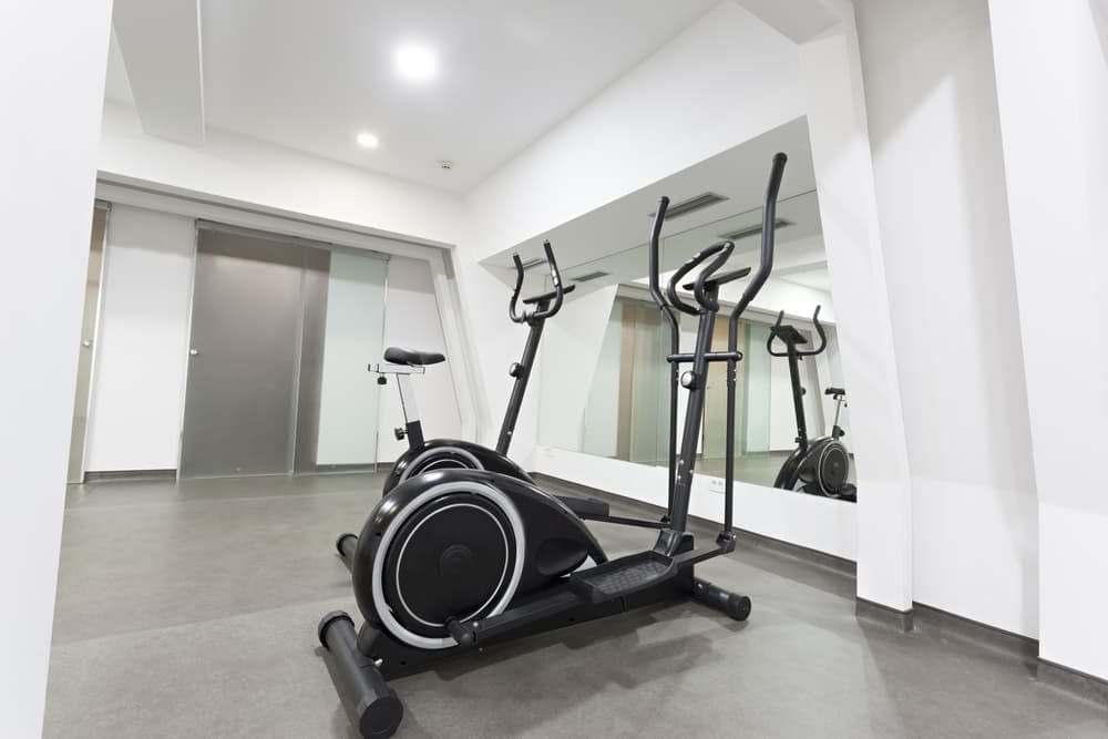 An elliptical and an exercise bike in a home gym with mirrors