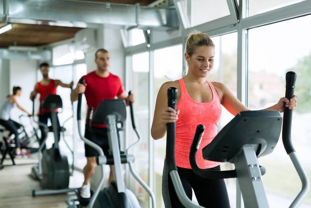 A group of people exercising on elliptical cross trainers in a gym