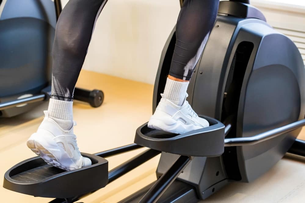 A pair of legs riding the front drive elliptical trainer